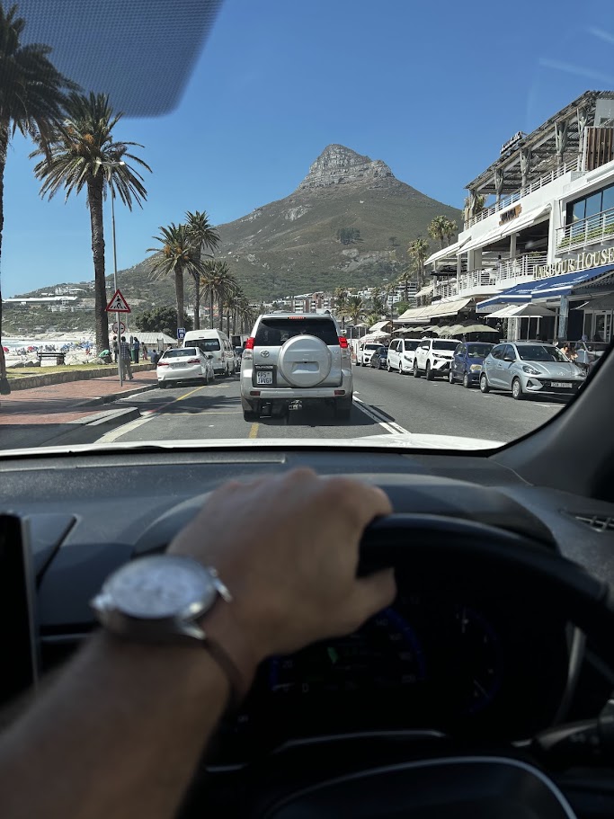 Hand aan het stuur tijdens een autorit door Camps Bay in Kaapstad, Zuid-Afrika