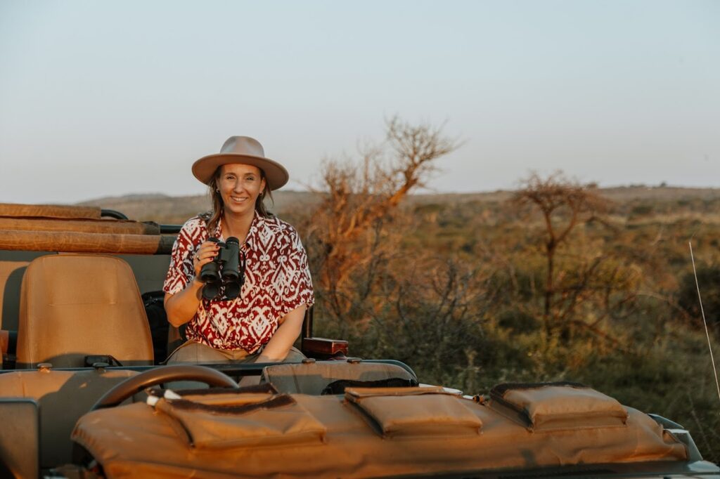 Roxanne van der Ven-Overdijk tijdens een safari in Zuid-Afrika met een verrekijker in een open safarivoertuig.